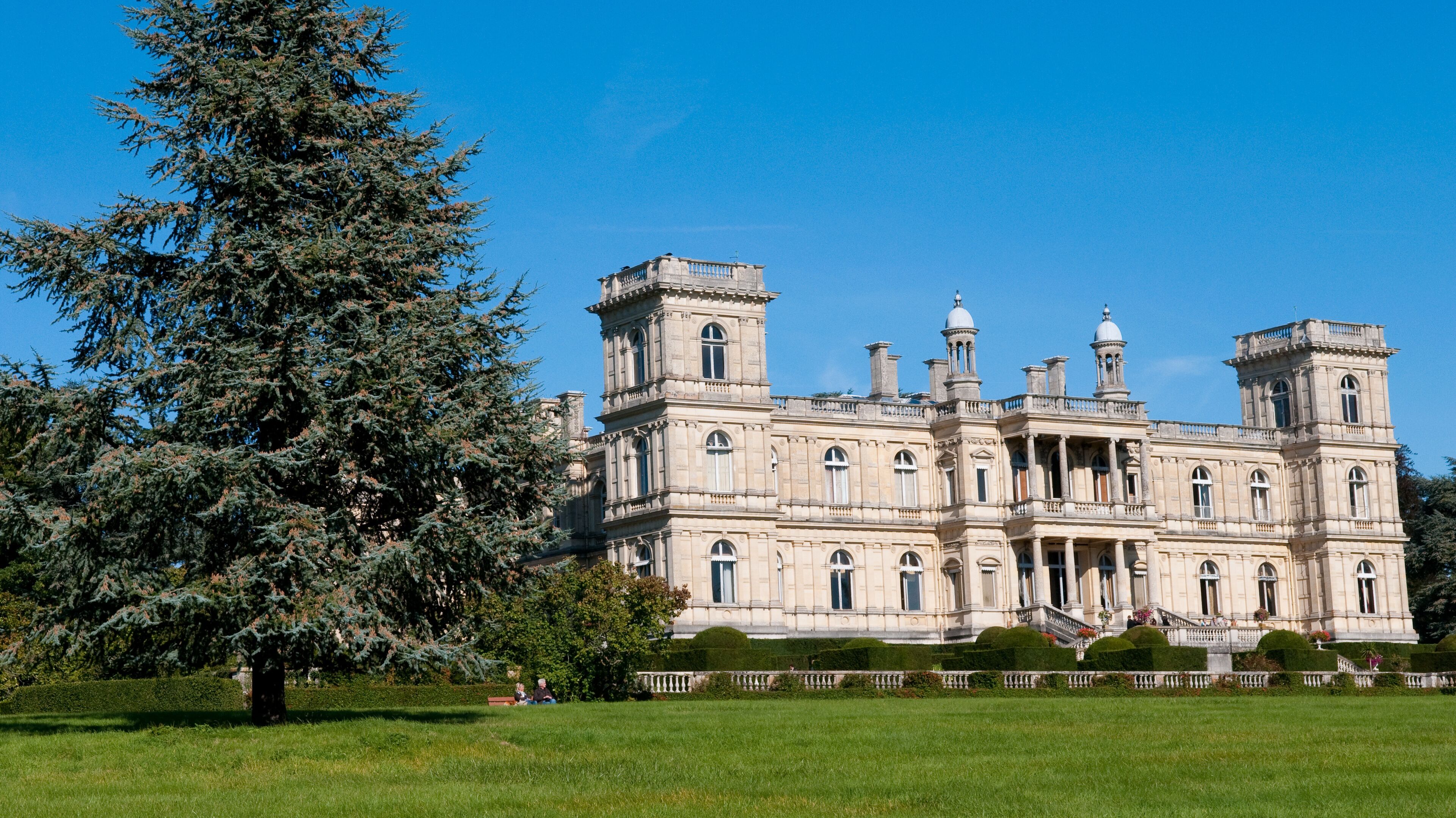 A large, ornate building with multiple towers and a well-manicured lawn.
