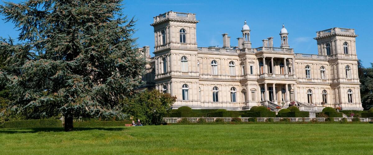 A large, ornate building with multiple towers and a well-manicured lawn.