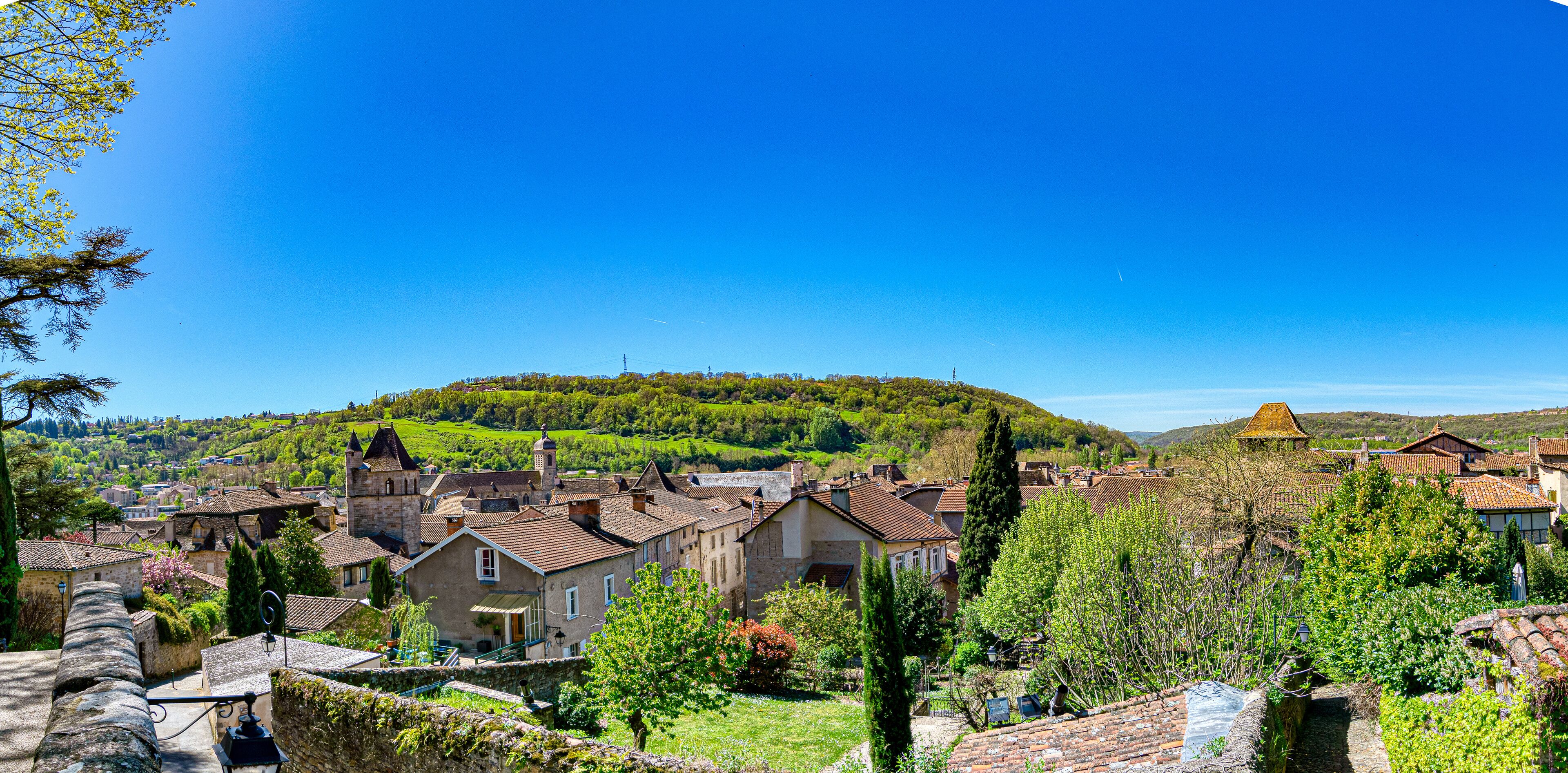 A picturesque village with traditional architecture, lush green hills, and a clear blue sky.