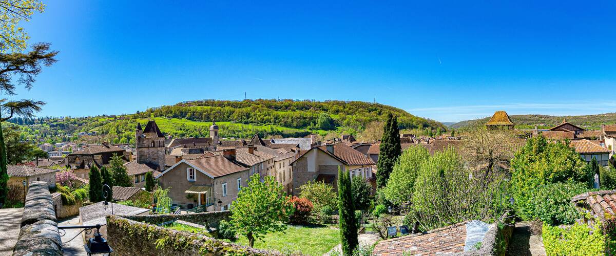 A picturesque village with traditional architecture, lush green hills, and a clear blue sky.