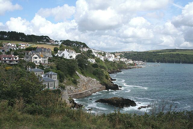 A coastal town with houses along the cliffside, a rocky shoreline, and a view of the sea.
