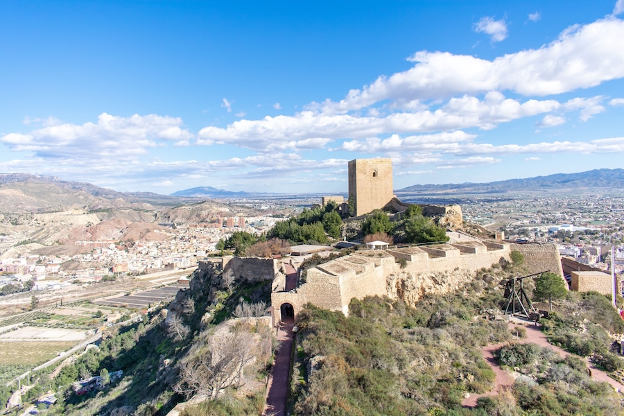 The view from another tower of Lorca Castle in southern Spain, shows the great tower and surrounding walls of the keep, with a trebuchet replica standing ready to attack.