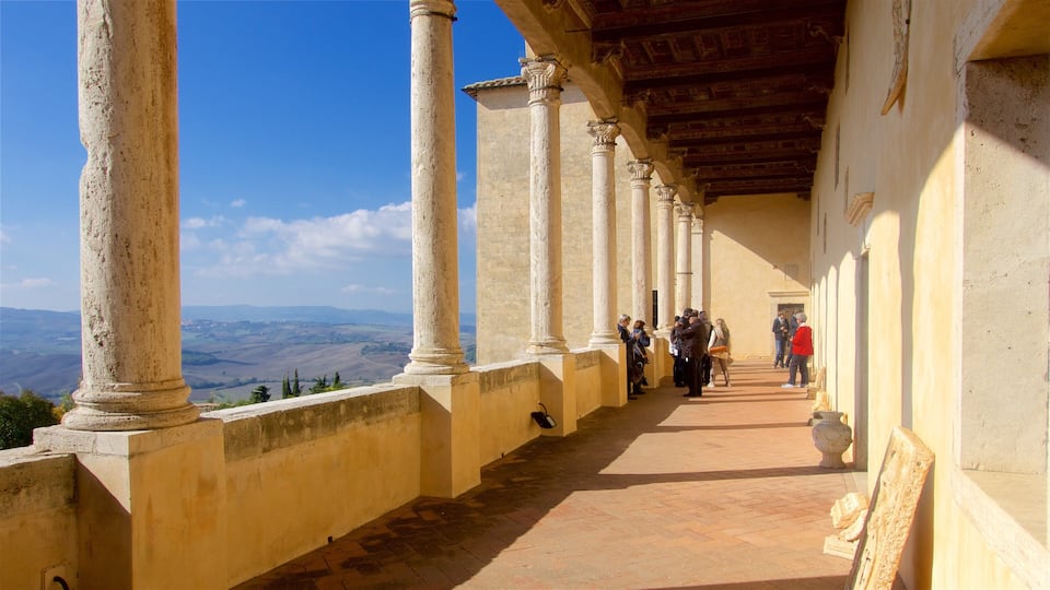 A corridor with columns, a tiled floor, and a view of distant hills.