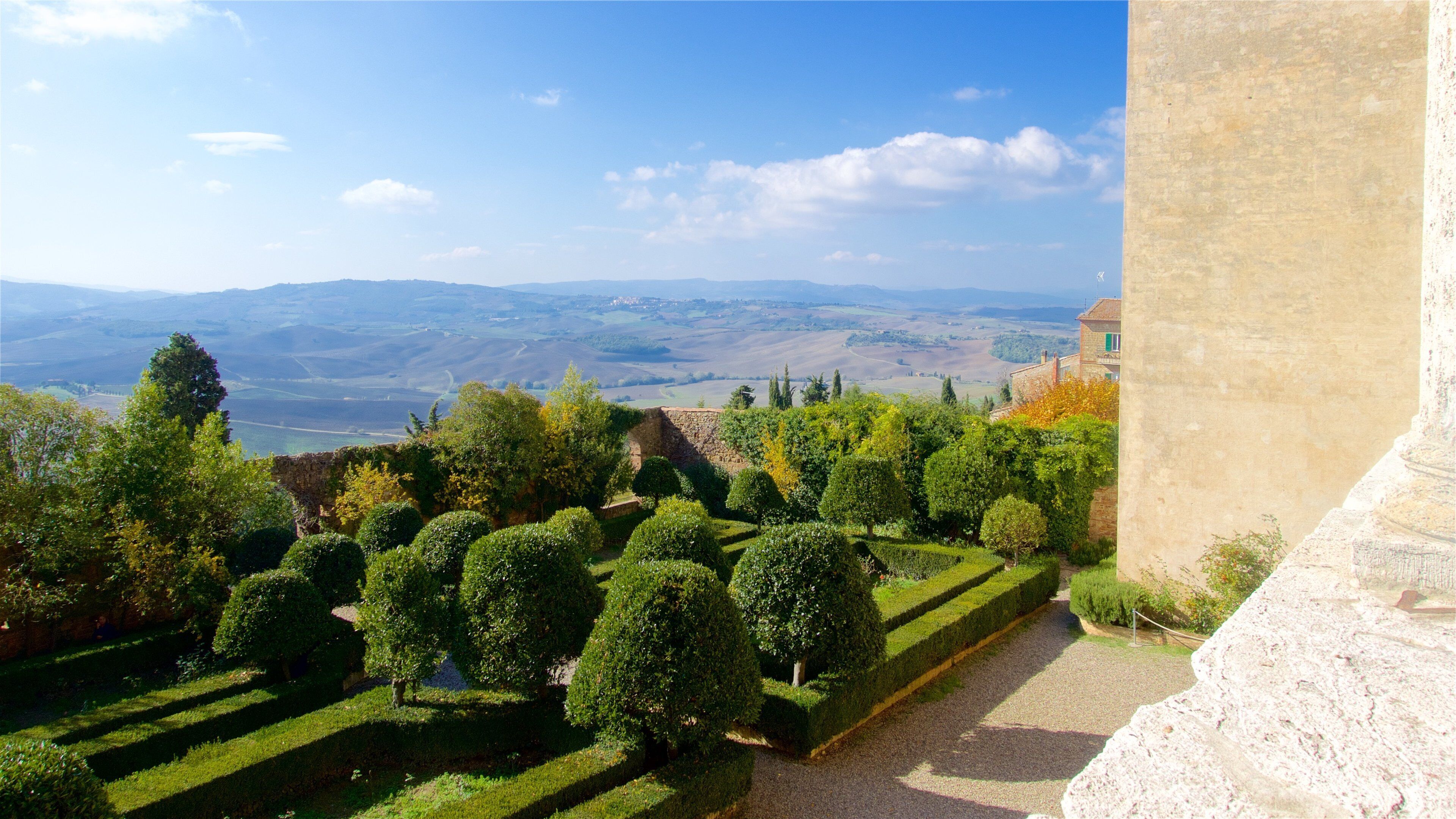 A terraced garden with neatly trimmed hedges and a stone wall.
