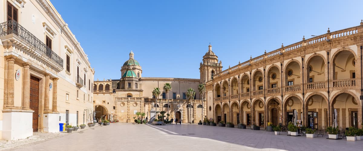 A historic plaza with a central dome, arches, and a covered walkway.