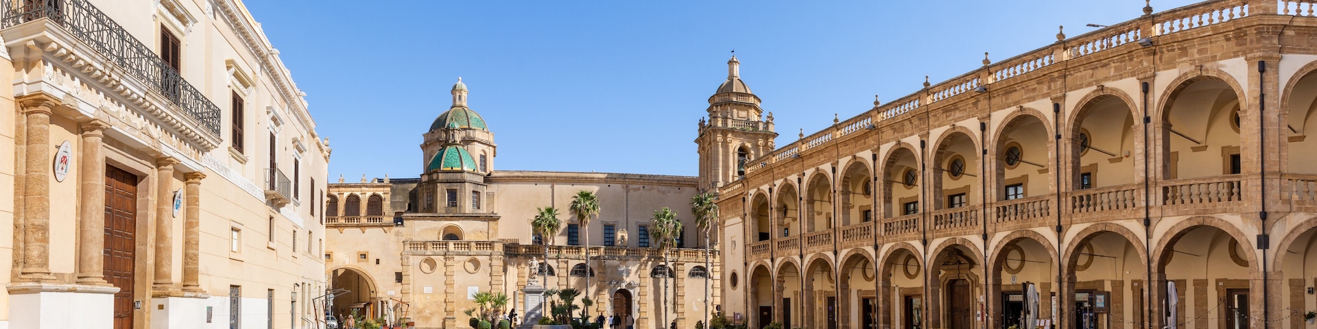 A historic plaza with a central dome, arches, and a covered walkway.