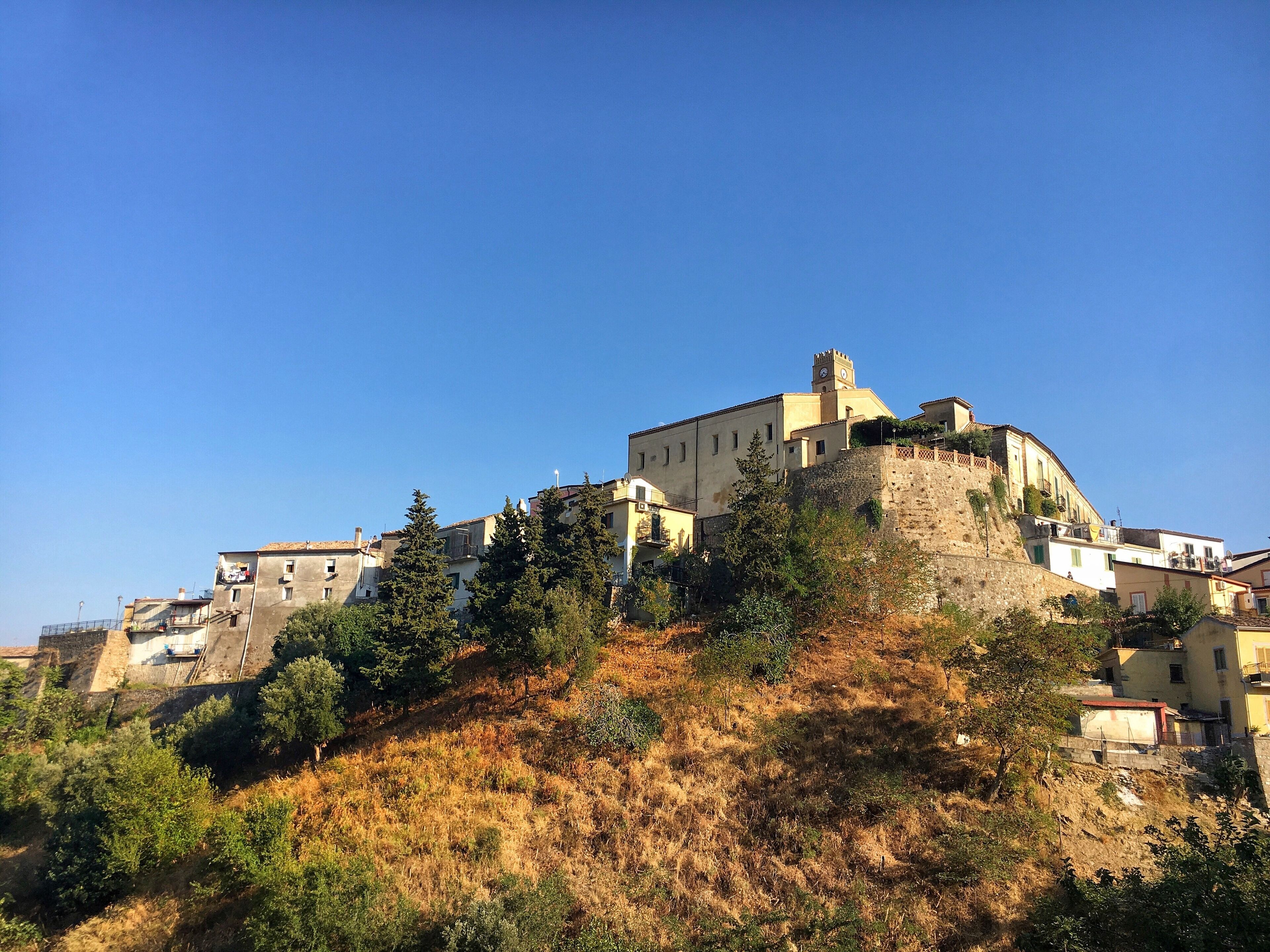 A historic castle on a hill with surrounding buildings and trees.