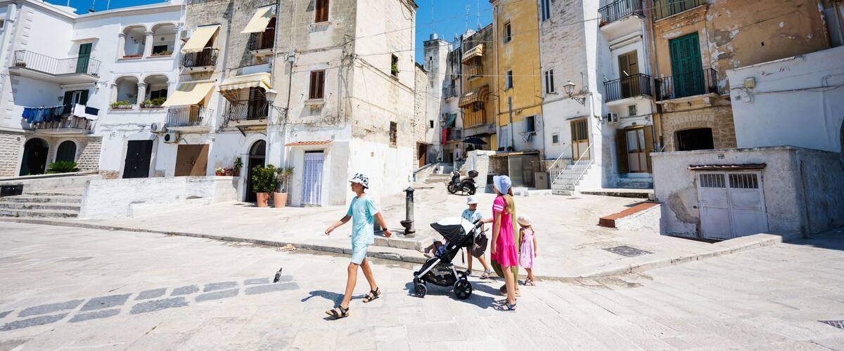 A pedestrian street with historic buildings, a stroller, and a clear blue sky.