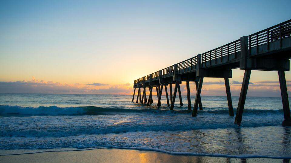 A pier extending into the ocean at sunset.