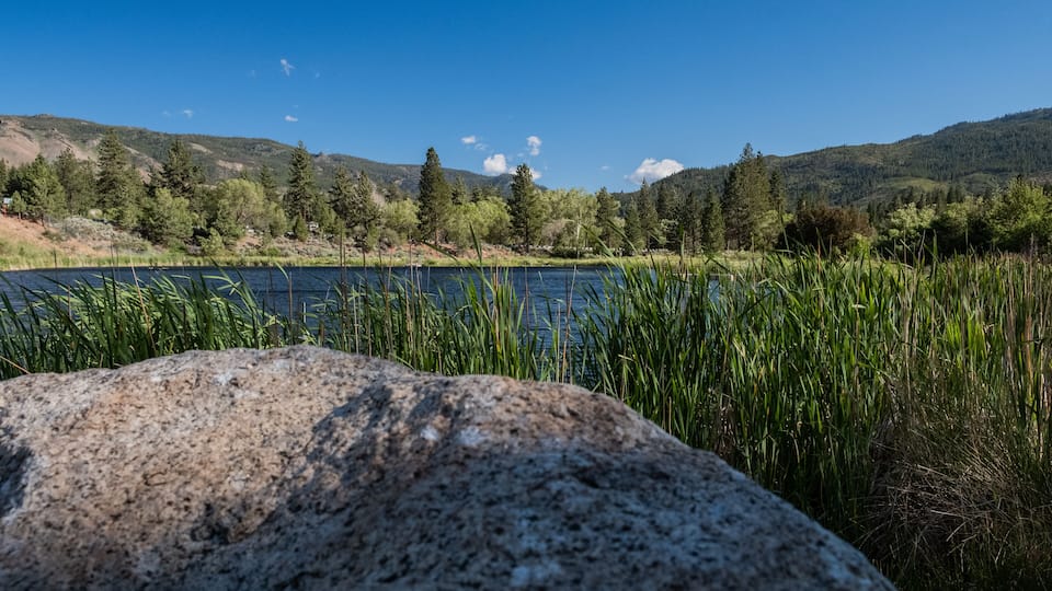 A lake with surrounding trees and mountains.