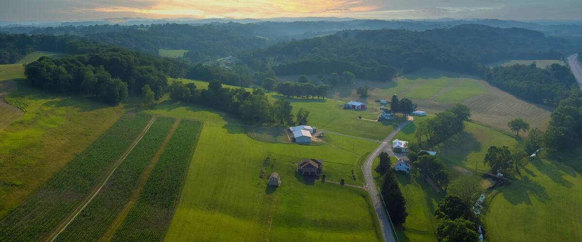 An aerial view of a rural landscape with fields, a road, and scattered buildings.