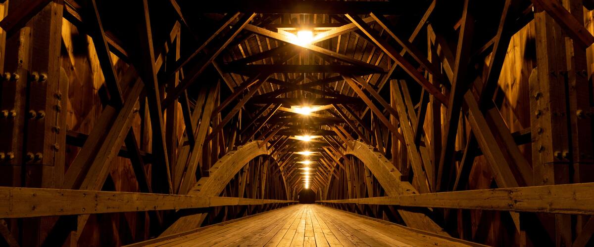 A wooden bridge with a wooden floor and a series of lights along the center.