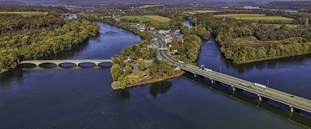 A river with a bridge and a small island with buildings.