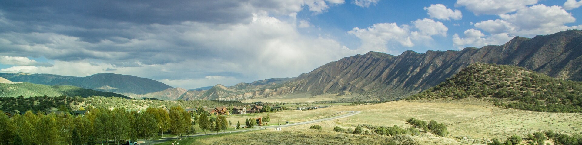 Un paisaje montañoso con una carretera, edificios y árboles.