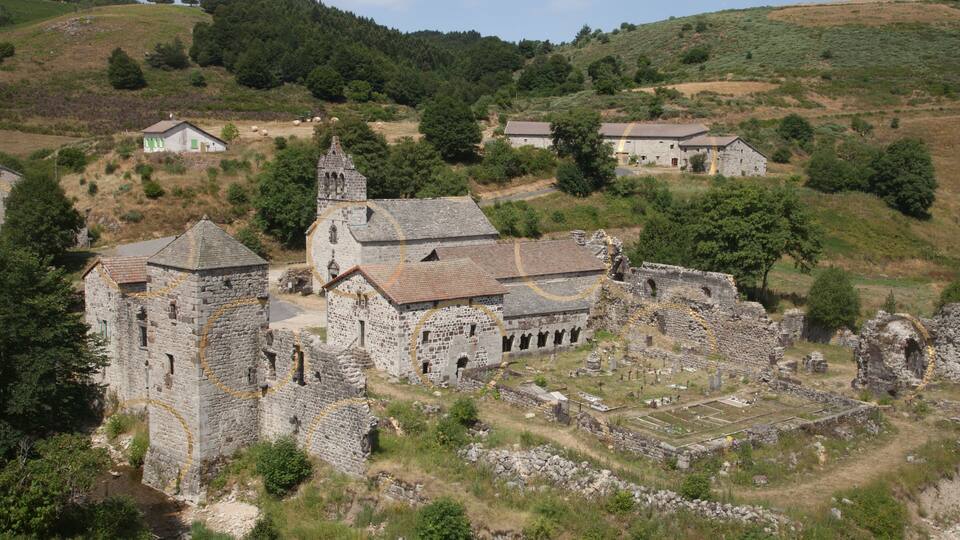 An ancient stone church with ruins and a surrounding landscape.