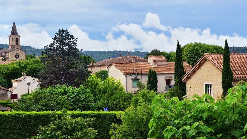 A village with traditional architecture, a church, and lush greenery.