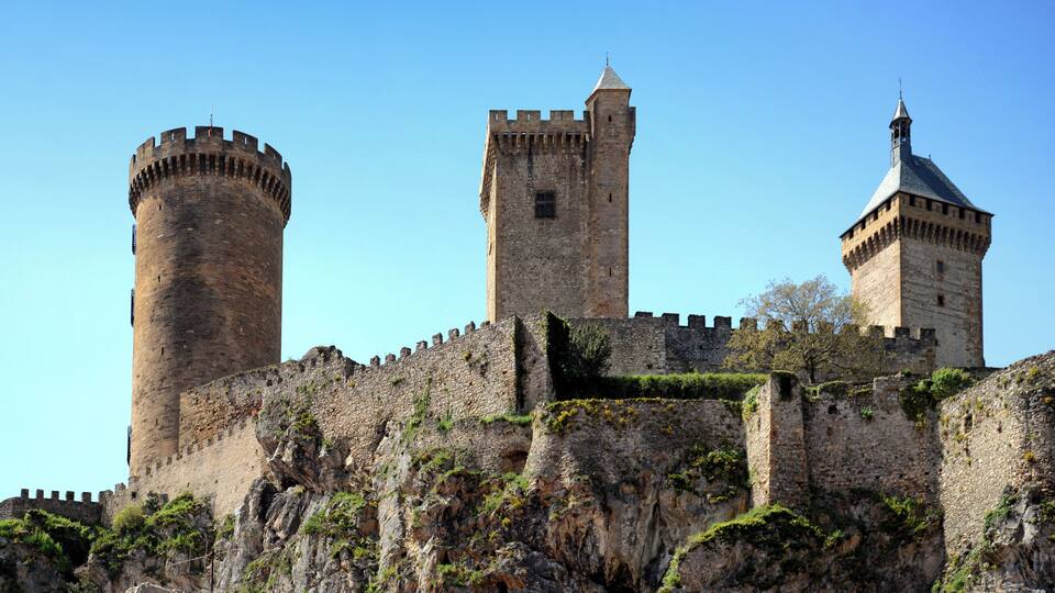 A historic castle with three towers and a fortified wall.