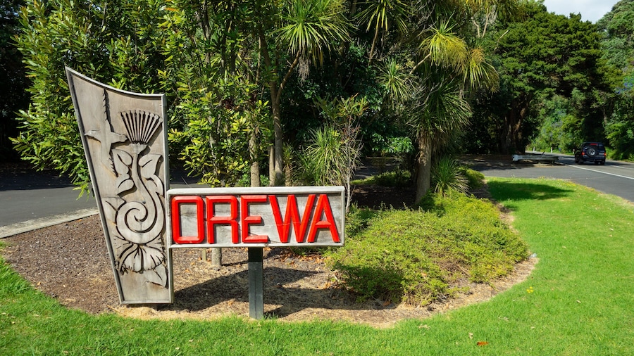 Ein Schild mit dem Wort "OPEWA" in roten Buchstaben, umgeben von Grünpflanzen und Bäumen.