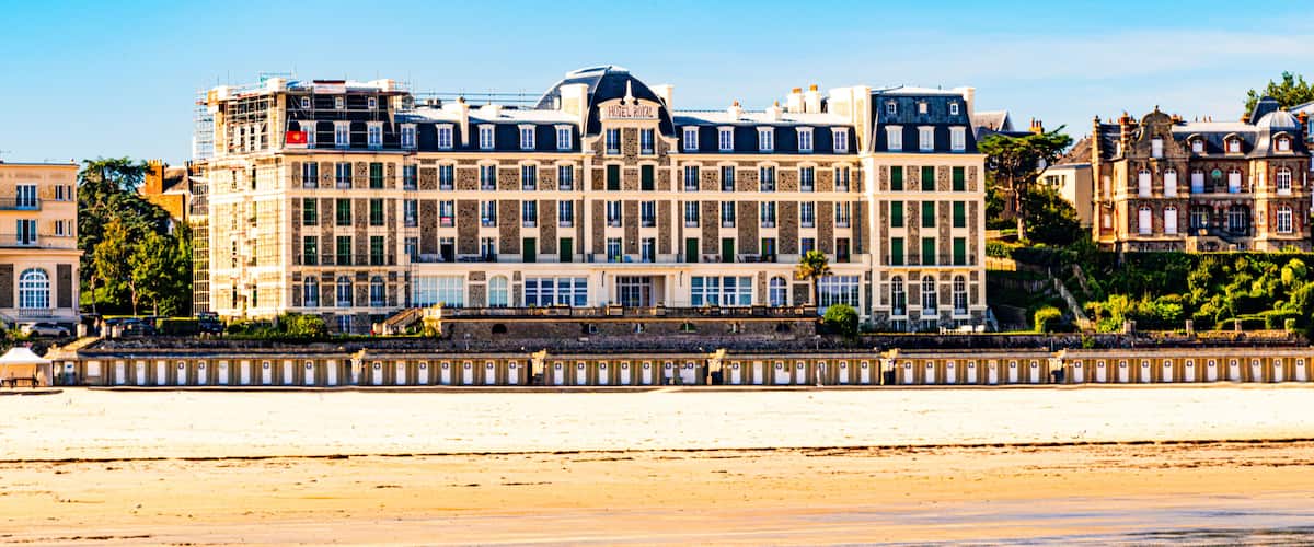 A large hotel with multiple stories and a beach in the foreground.