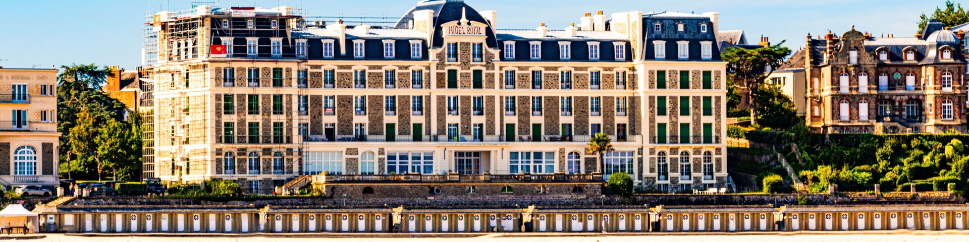 A large hotel with multiple stories and a beach in the foreground.