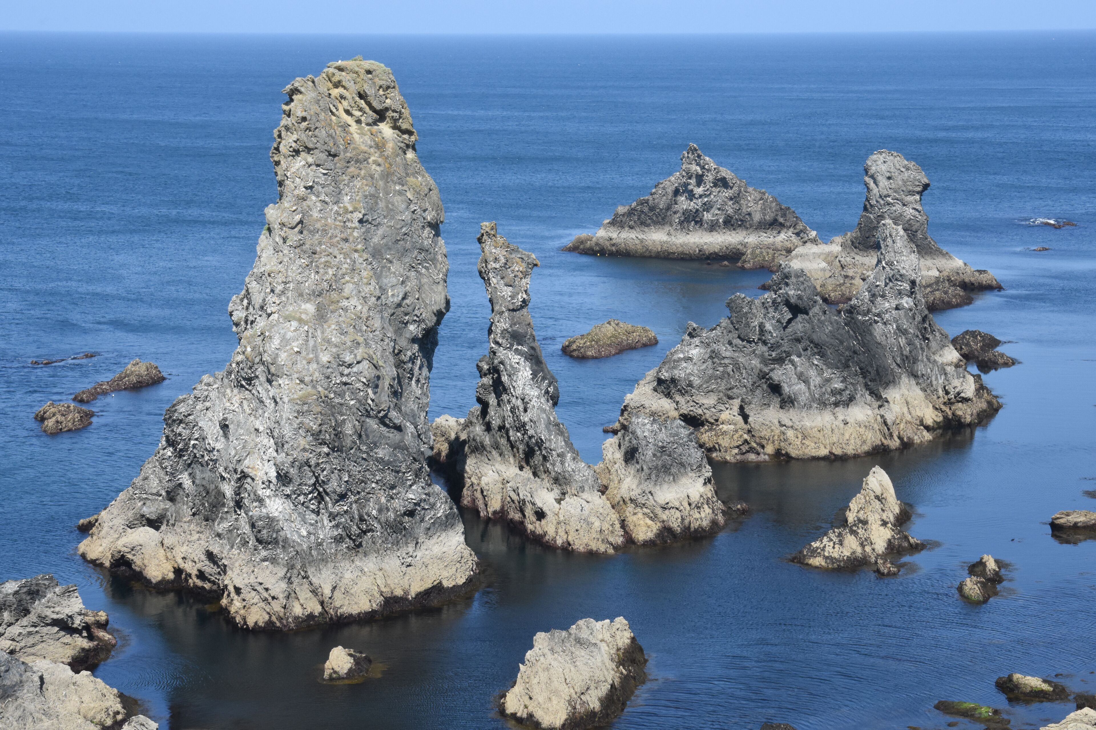 A coastal landscape with prominent rock formations and calm sea.