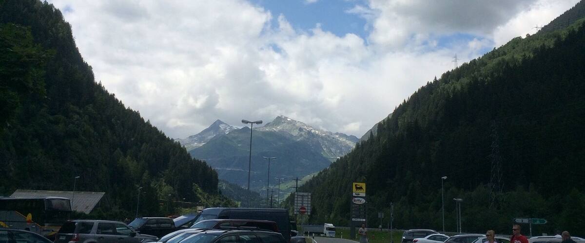 A parking lot with cars, a road, and a mountainous landscape in the background.