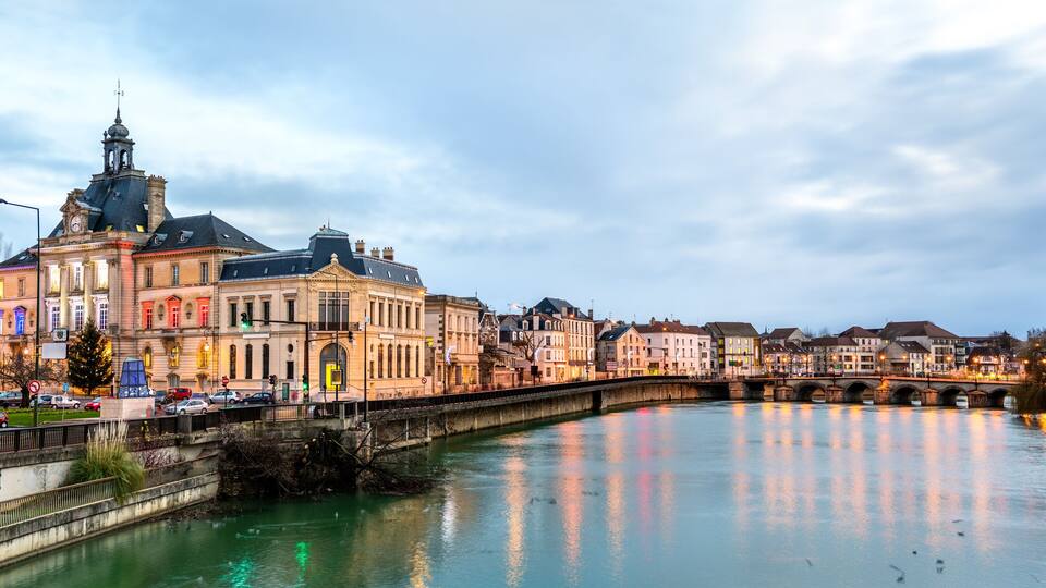 A river with a bridge, historic buildings, and a clock tower.