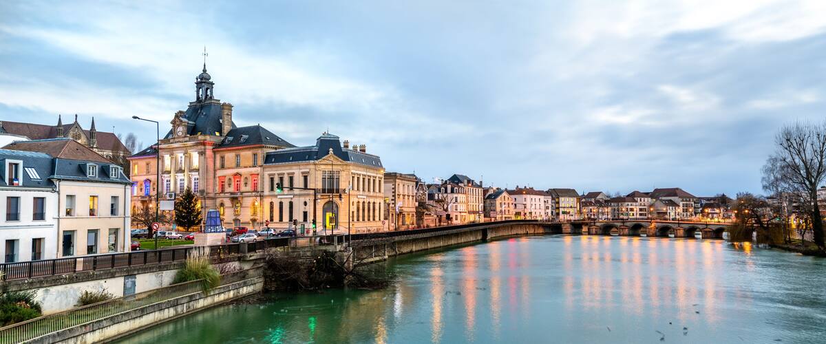 A river with a bridge, historic buildings, and a clock tower.