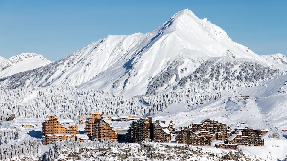 A snow-covered mountain with a ski resort in the foreground.
