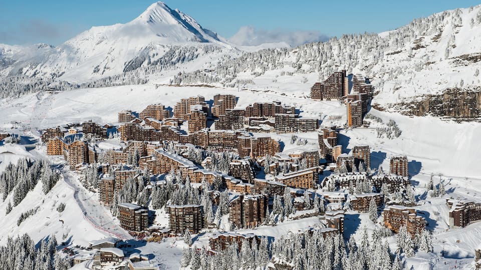 A snow-covered mountain town with ski slopes and buildings.