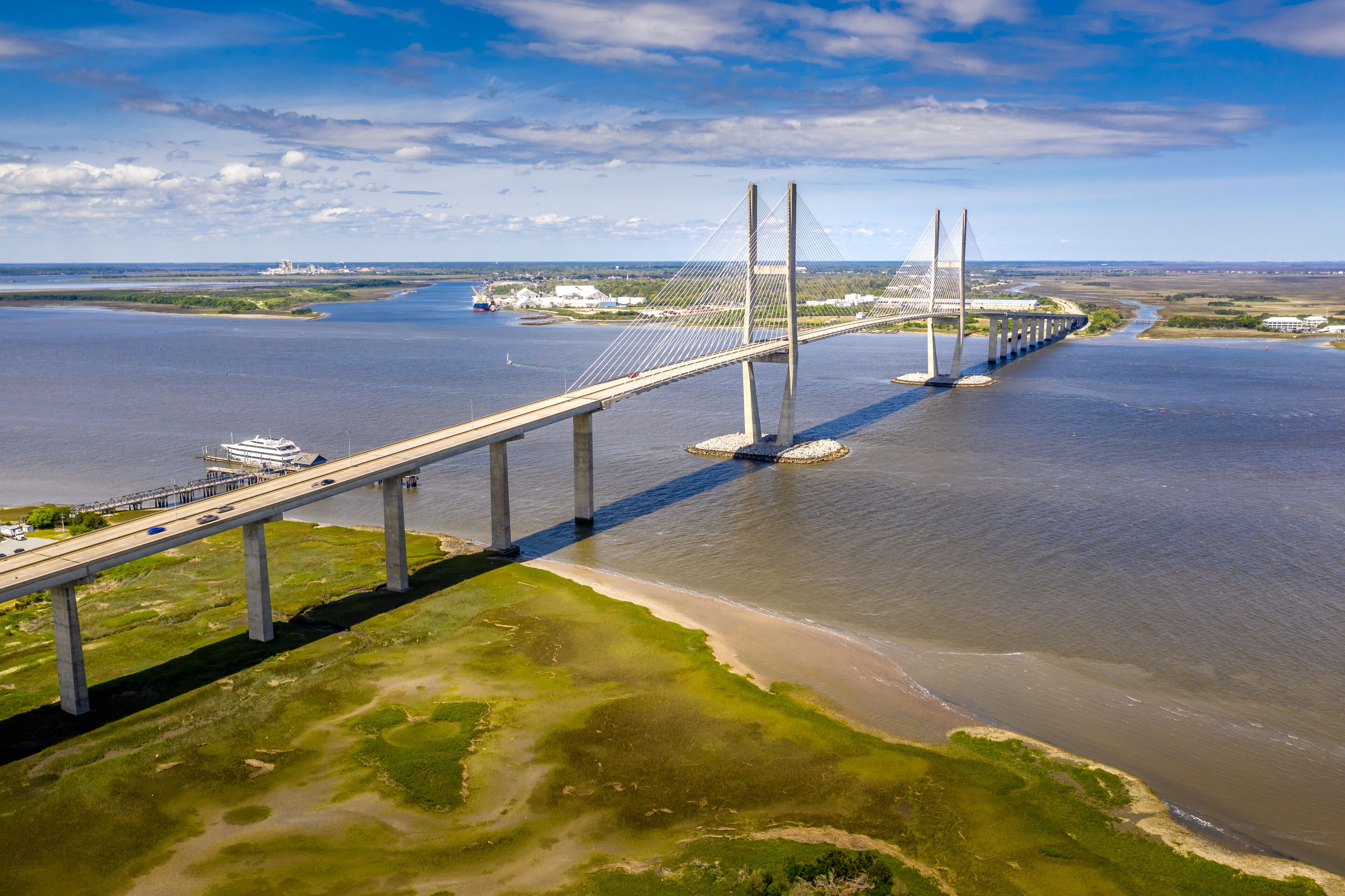 A long bridge spanning a wide river with a clear sky and distant land.