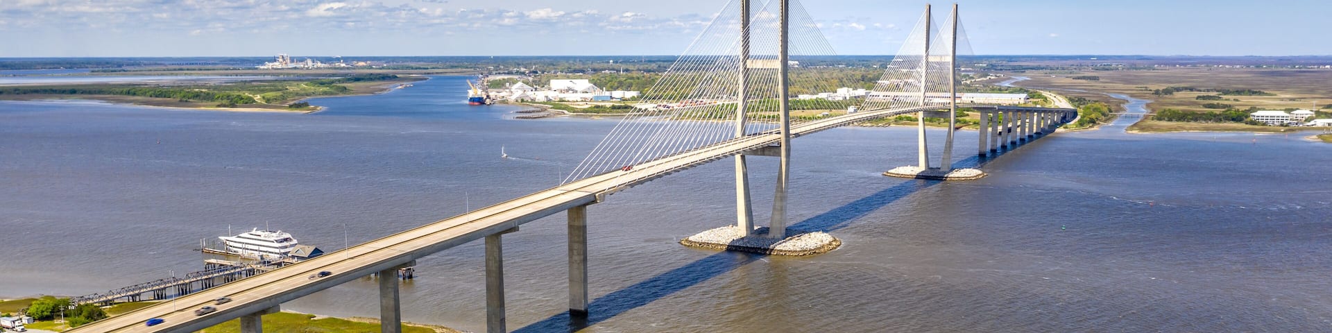 A long bridge spanning a wide river with a clear sky and distant land.