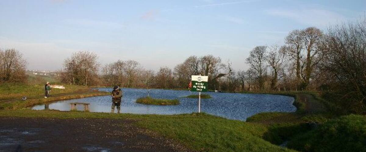 A flooded area with a signpost and a person standing by a pond.