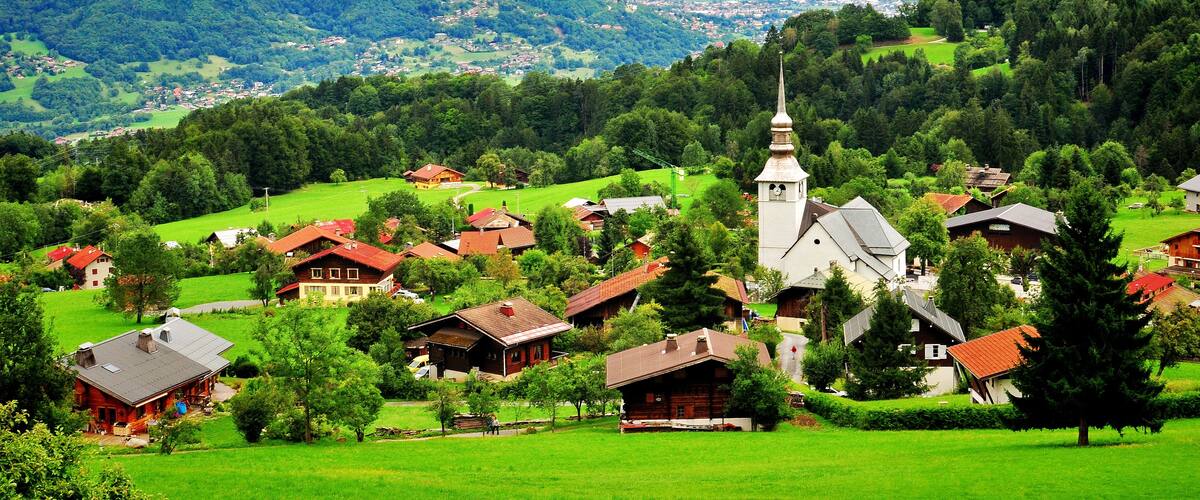A village with houses, a church, and mountains in the background.