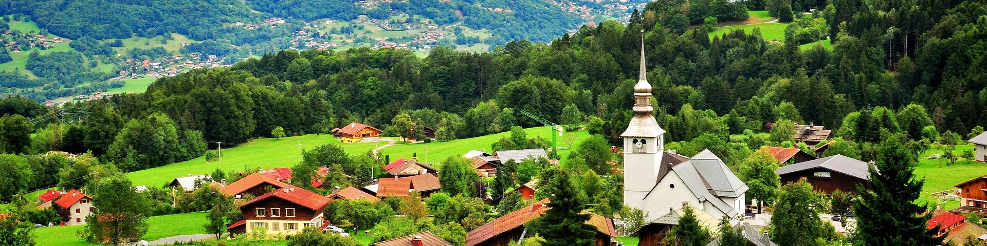 A village with houses, a church, and mountains in the background.