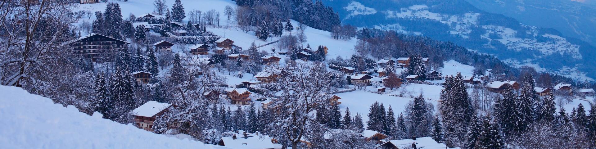 A snow-covered mountain range with a village nestled in the valley.
