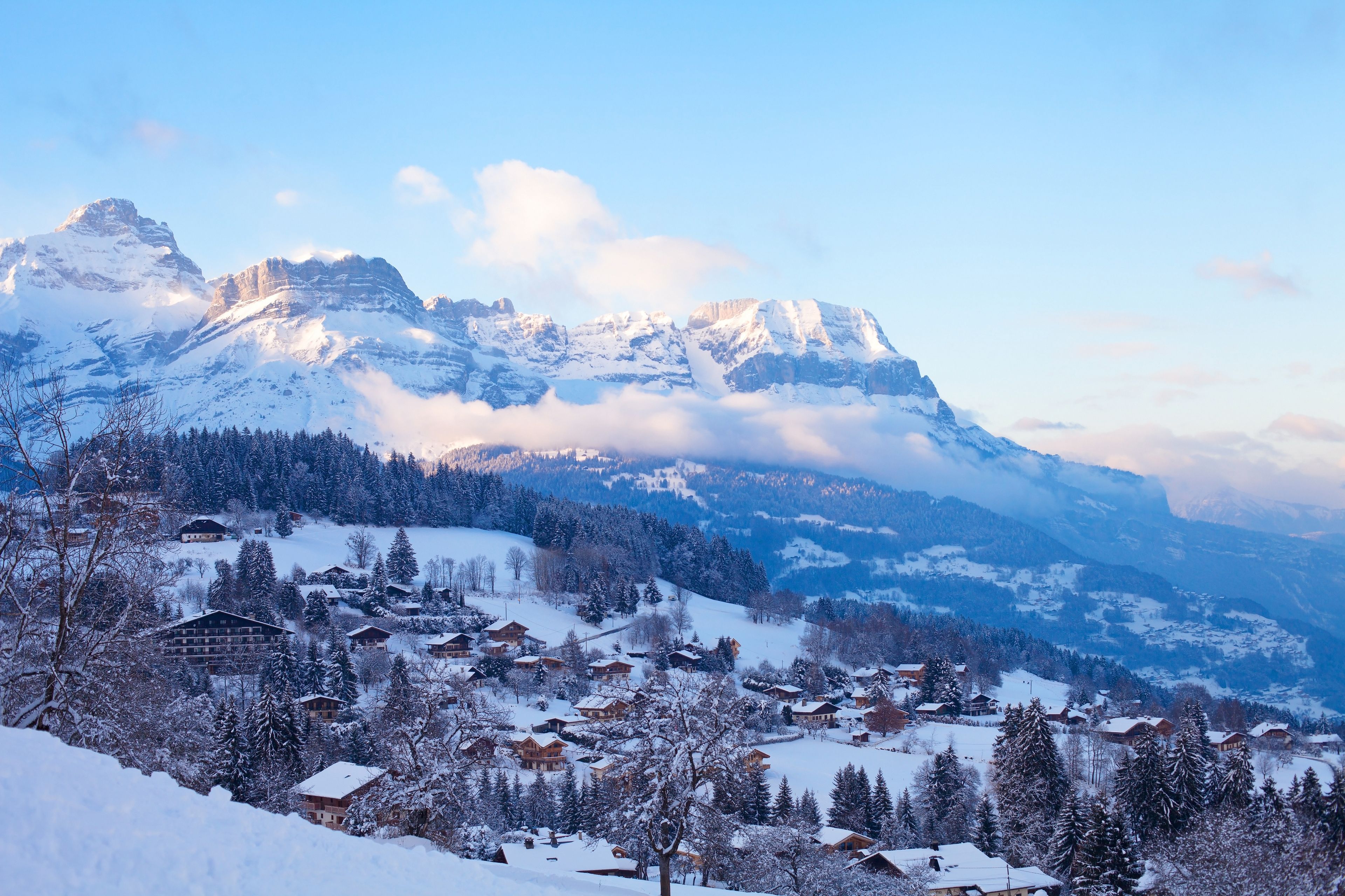 A snow-covered mountain range with a village nestled in the valley.