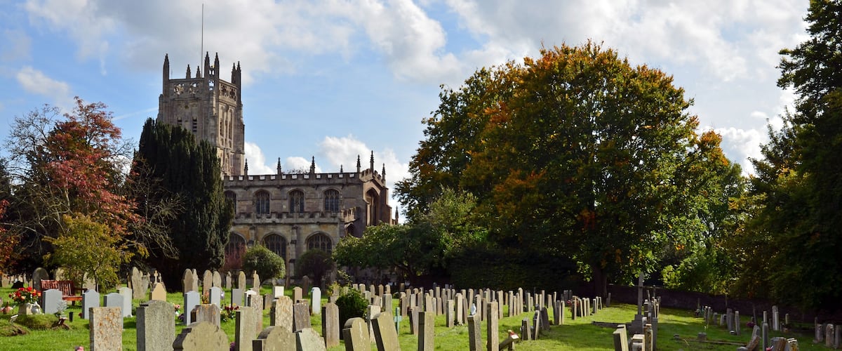 A cemetery with numerous headstones and a historic church in the background.