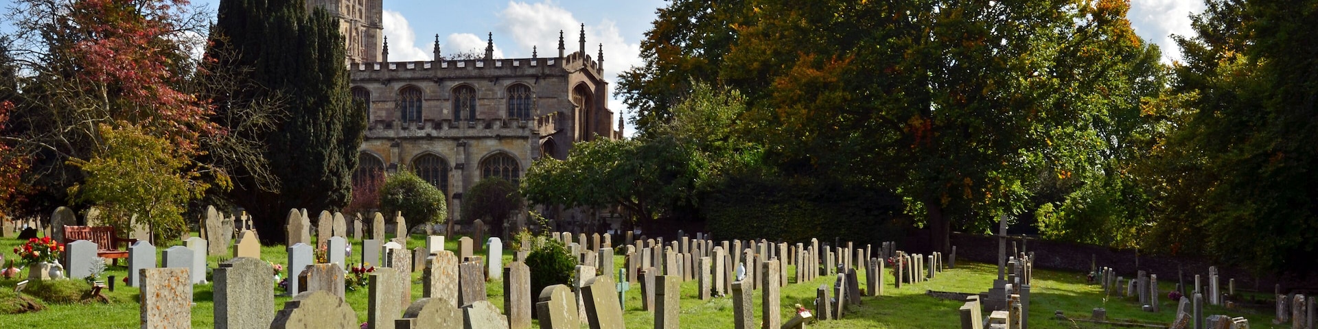 A cemetery with numerous headstones and a historic church in the background.