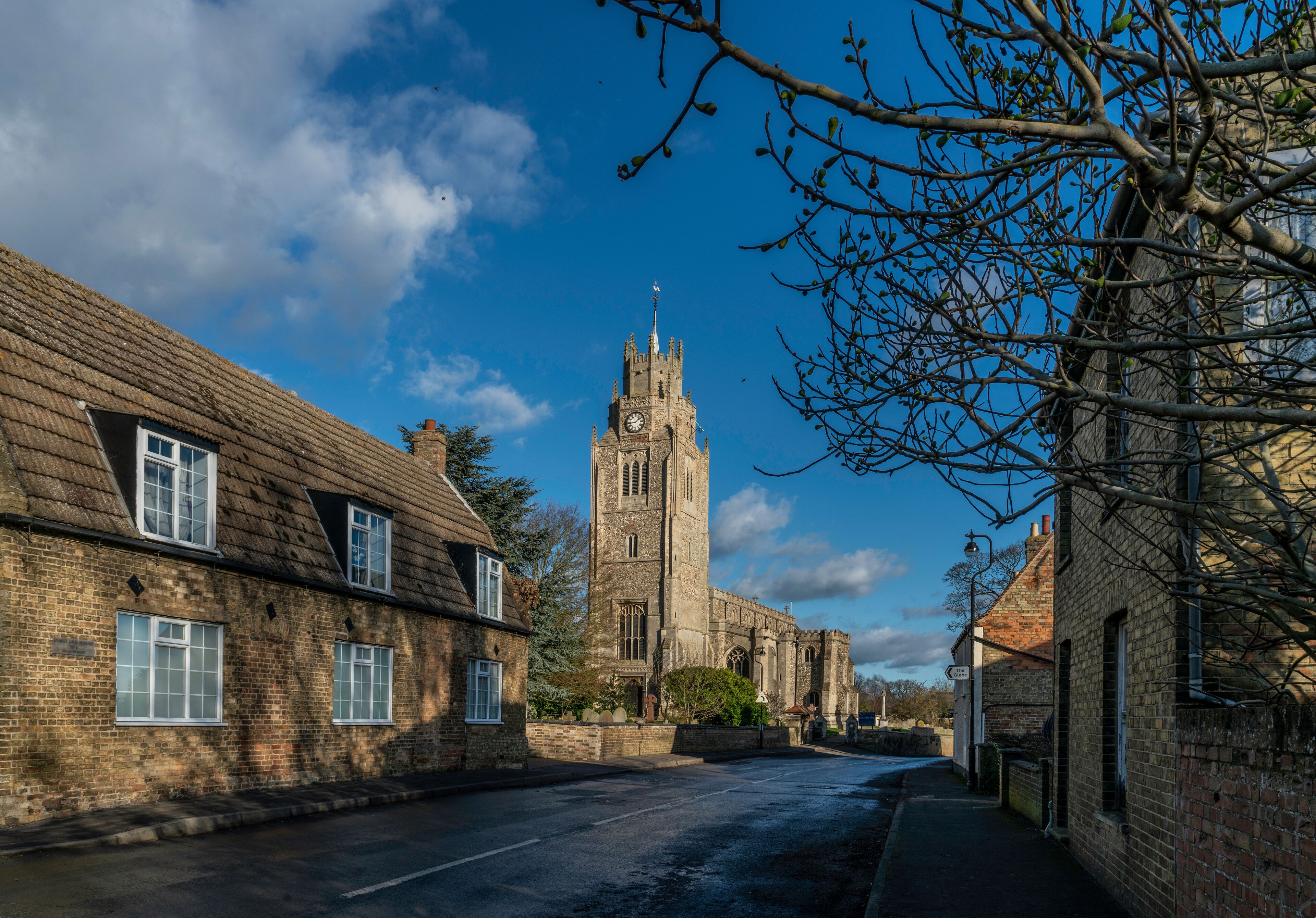 A historic church with a tall tower and a clock, surrounded by traditional brick buildings.