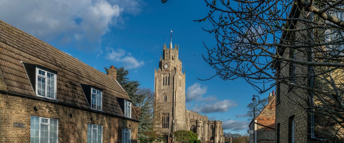 A historic church with a tall tower and a clock, surrounded by traditional brick buildings.