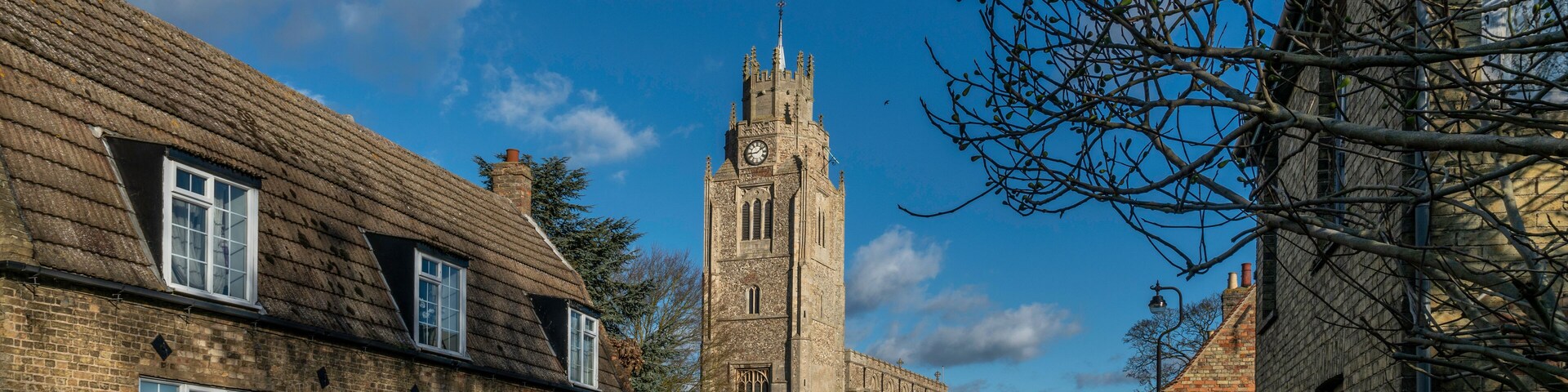 A historic church with a tall tower and a clock, surrounded by traditional brick buildings.