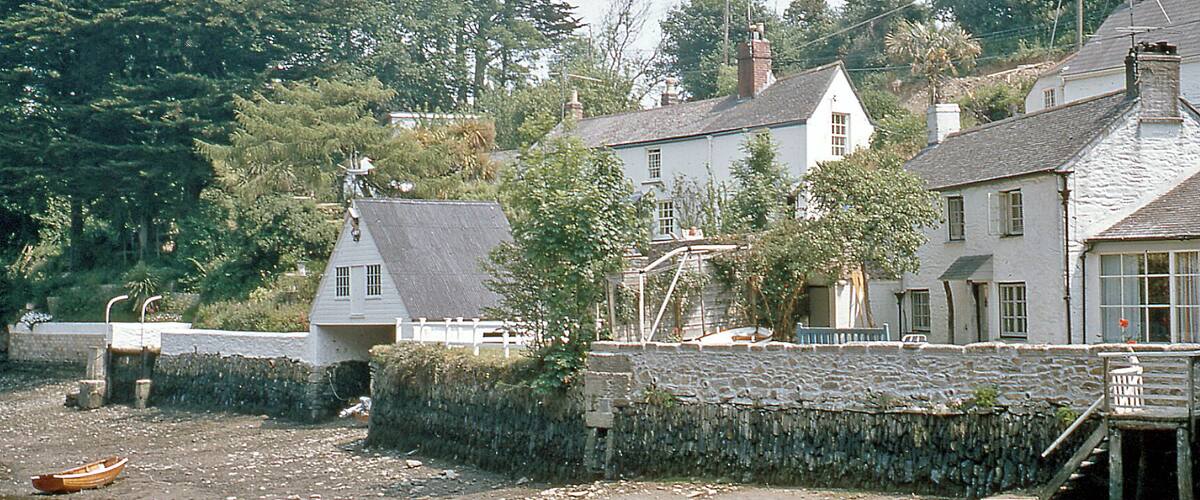 A coastal village with stone walls, a boat on the shore, and houses with sloped roofs.