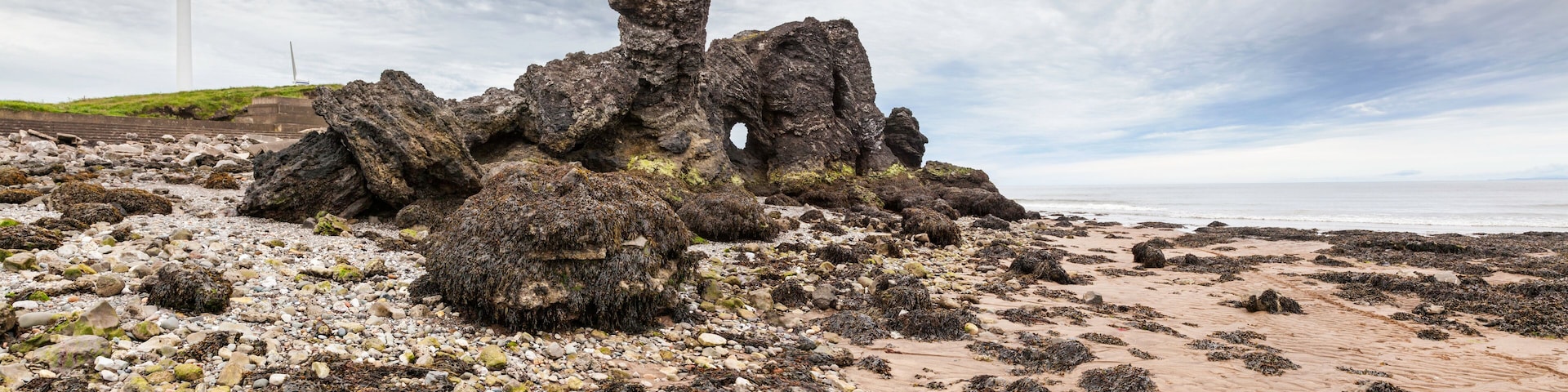A rocky coastline with wind turbines in the background.
