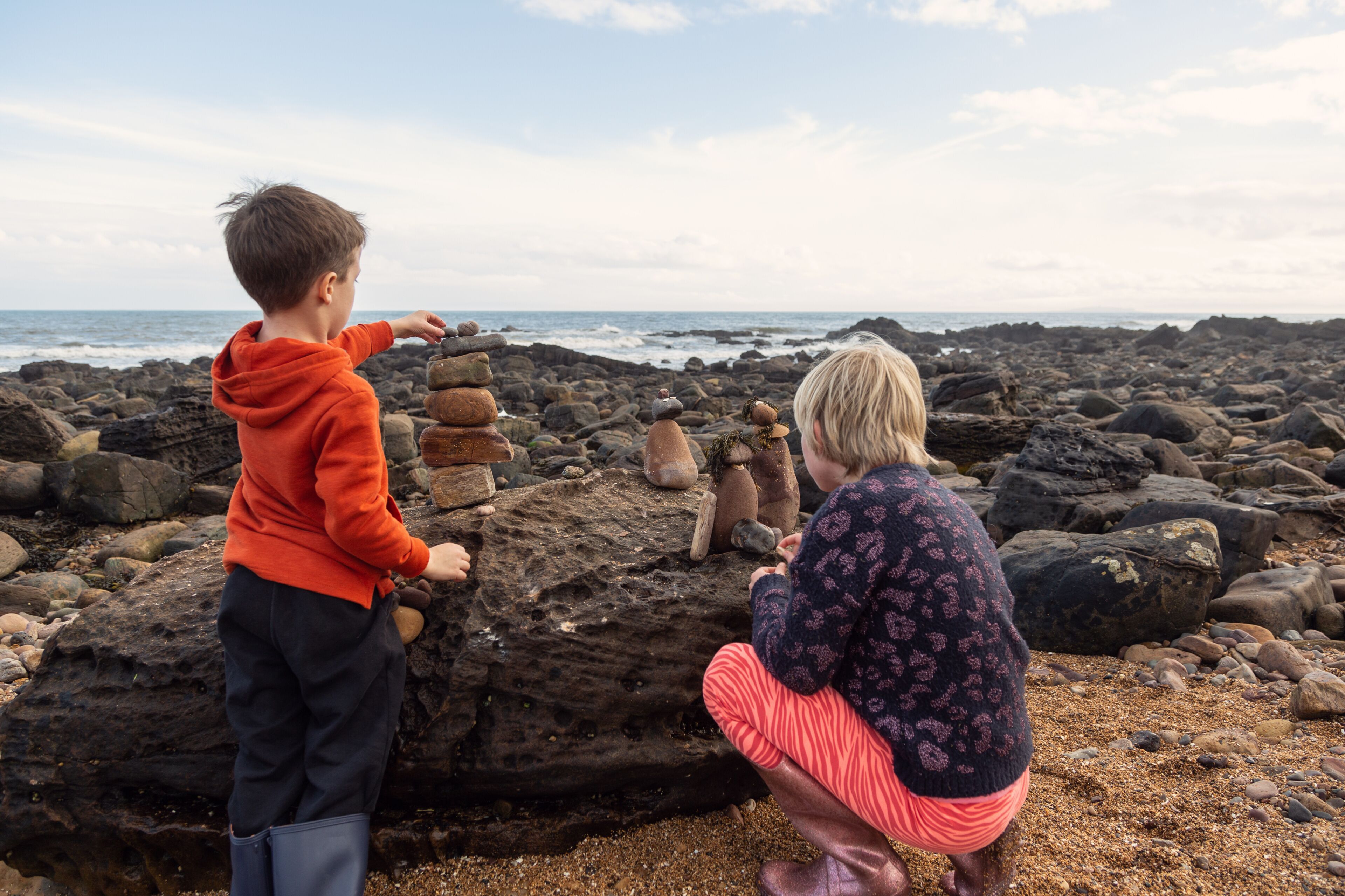 Siblings putting the finishing touches to their little rock people creations. This is a great way to spend time on a beach holiday.