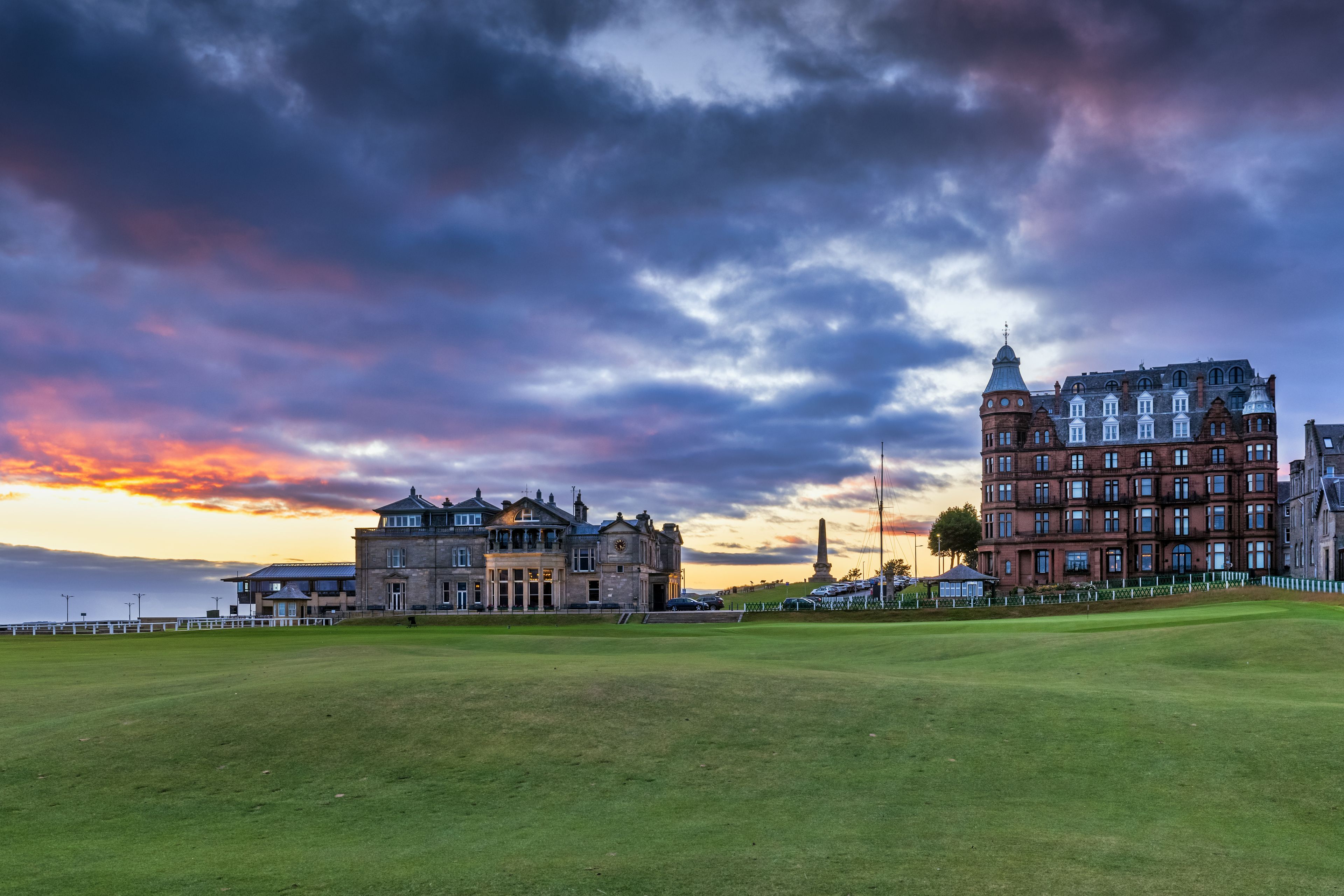 A historic building complex with a large lawn in the foreground.