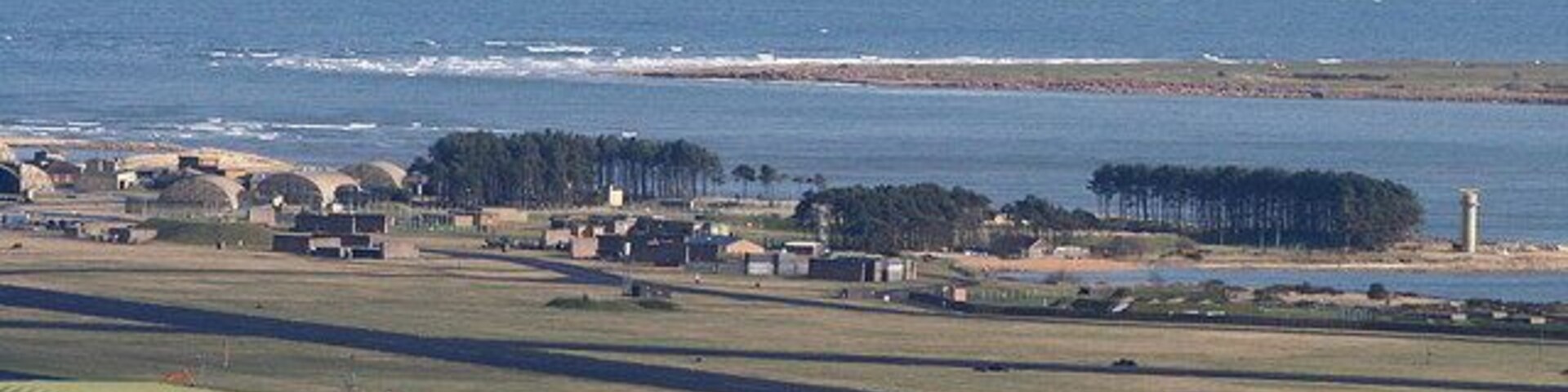 Un pueblo costero con un puerto, un barco grande y un faro.