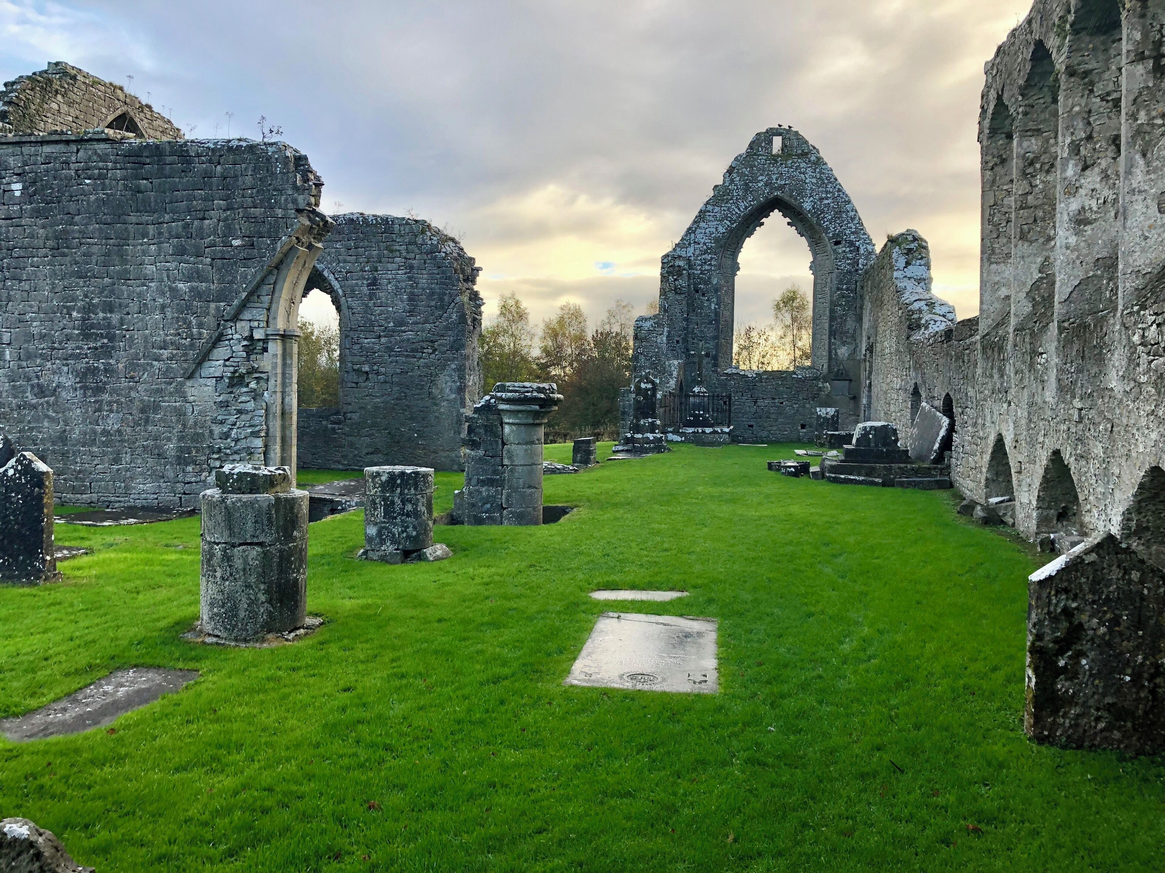 The ruins of an old stone structure with arched doorways and a grassy courtyard.