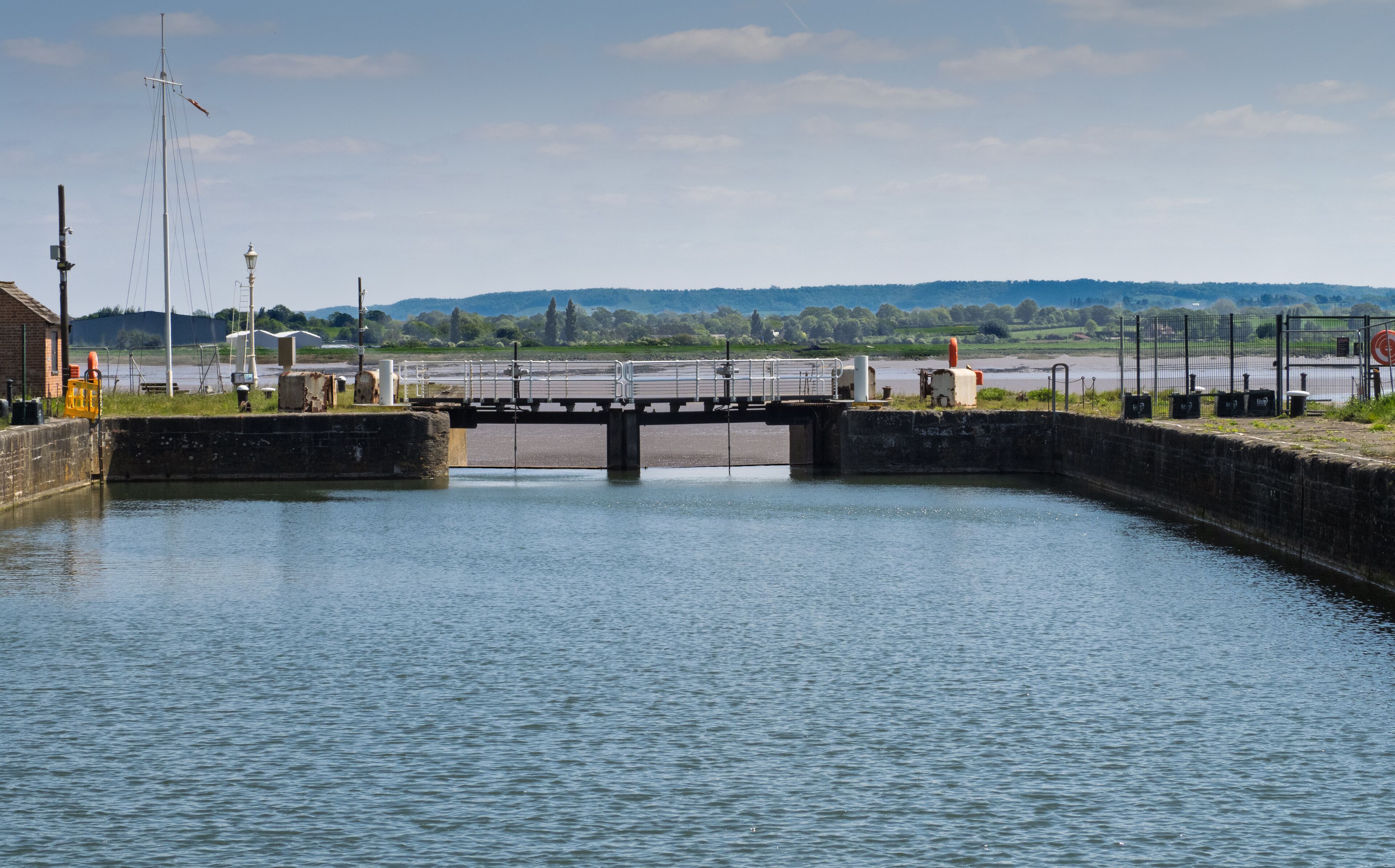 A canal lock with a bridge, water, and industrial structures in the background.