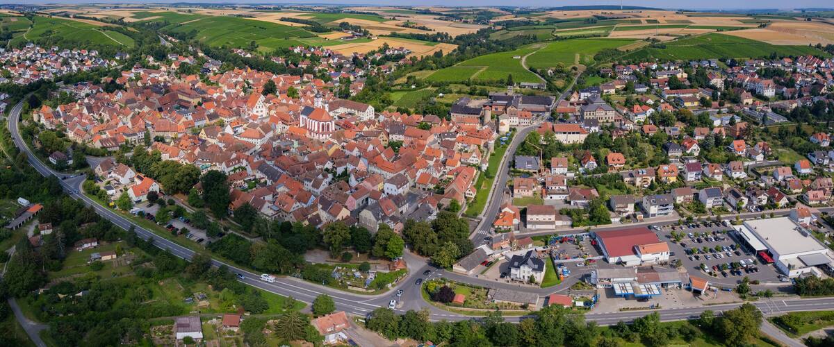 A river winding through a town with red-roofed houses and green fields.